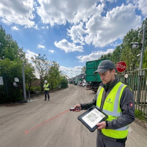 Ipari sorompó kivitelezés - 2. lépés: helyszíni felmérés lézeres távolságmérővel és digitális tervrajzot mutató ipari tablettel egy üzemi telephely beléptető kapujánál – Koffenstein Kaputechnika Kft.