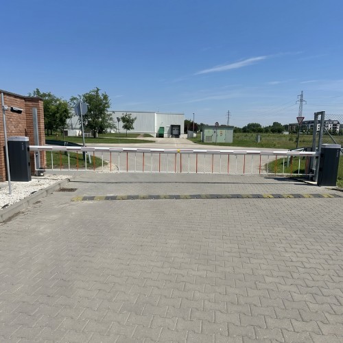 Biztonságos és automatizált ipari beléptetés: rácsos védőszoknyával és sebességkorlátozó jelzéssel ellátott CAME ipari sorompórendszer egy logisztikai központ és gyártelep bejáratánál – Koffenstein Kaputechnika Kft.